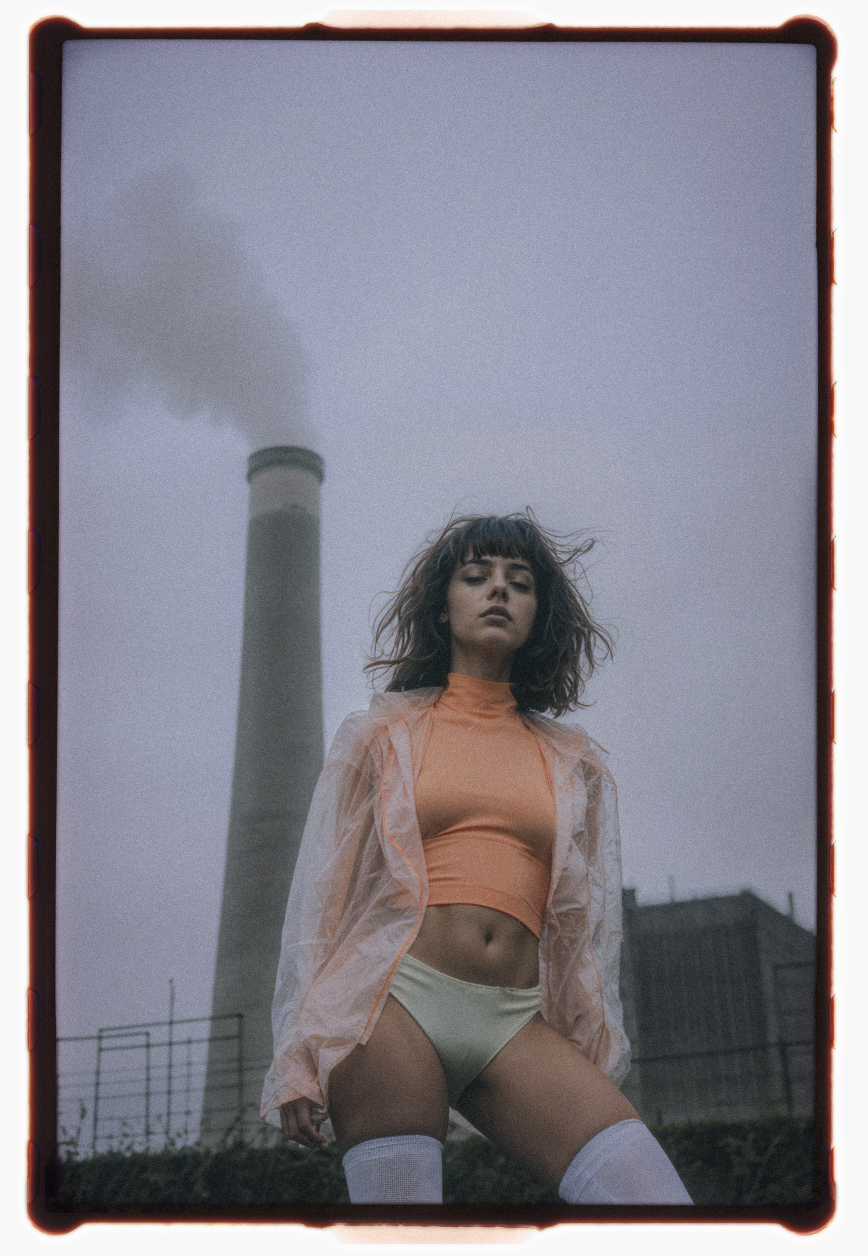 Analog portrait titled Chords of a model in bold fashion against an industrial smokestack backdrop.