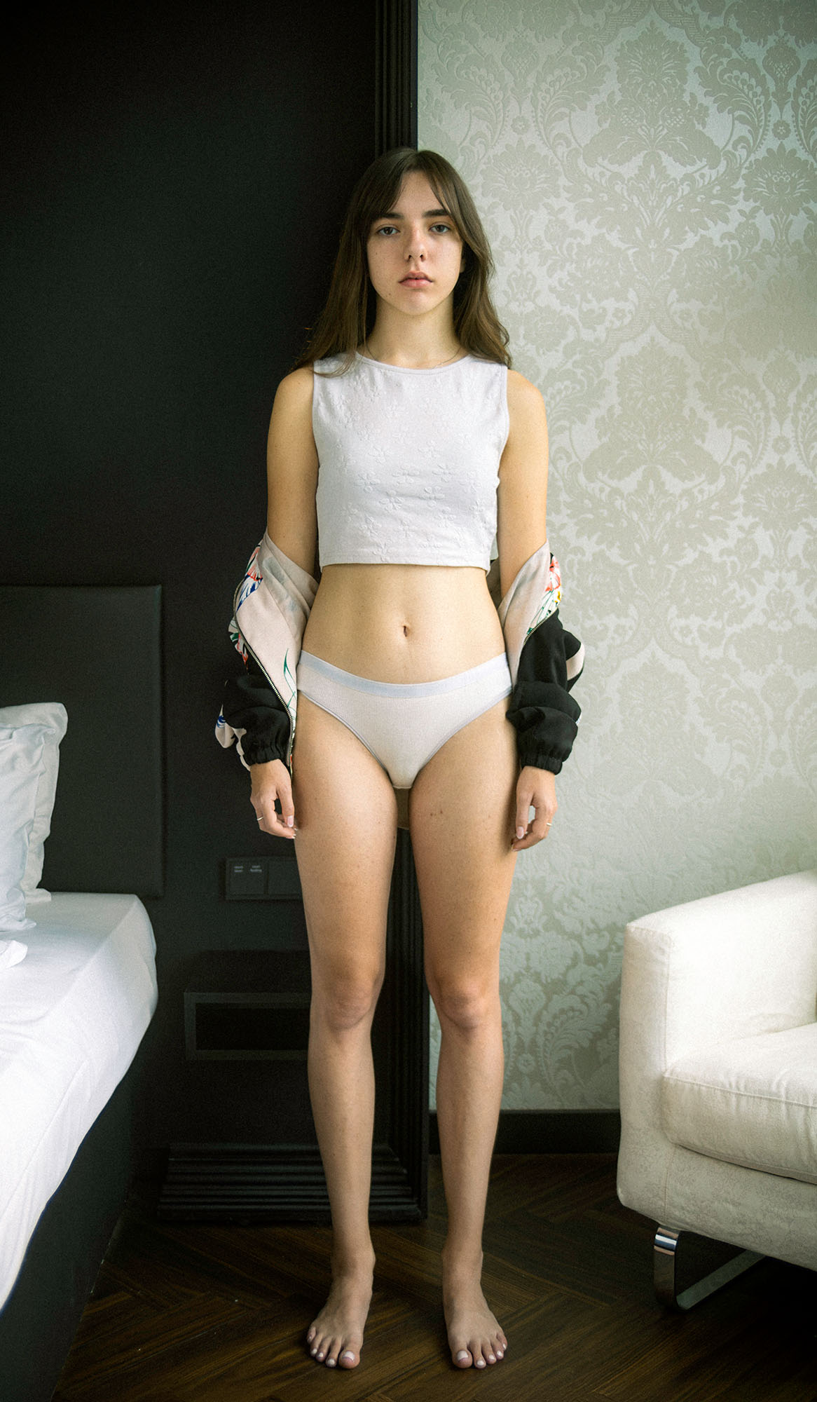 Conceptual portrait of a young woman posed uncomfortably wearing only underwear.